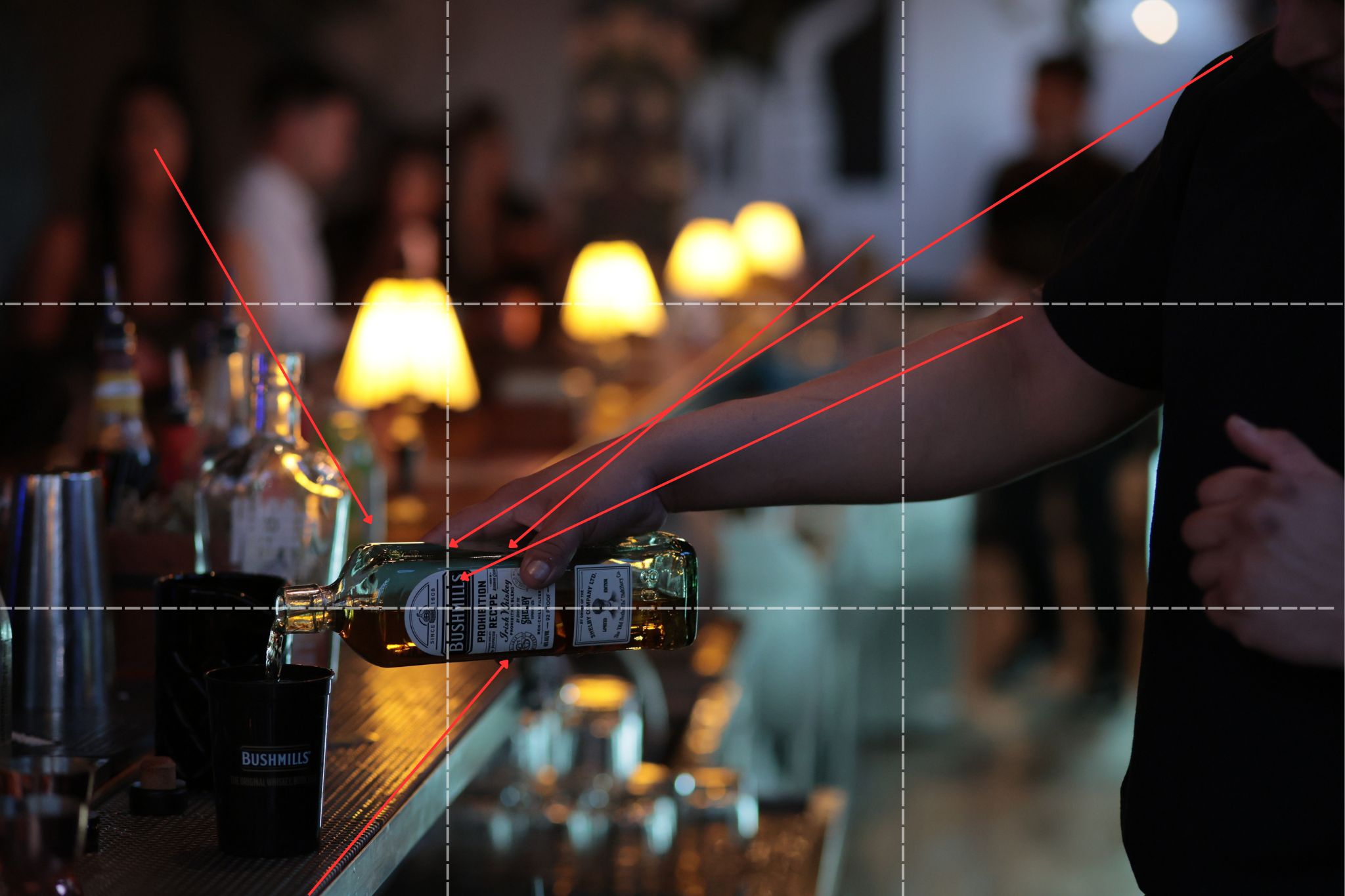 The same bar photo with markup lines drawn on it, showing leading lines converging on the Bushmills bottle and a rule-of-thirds grid